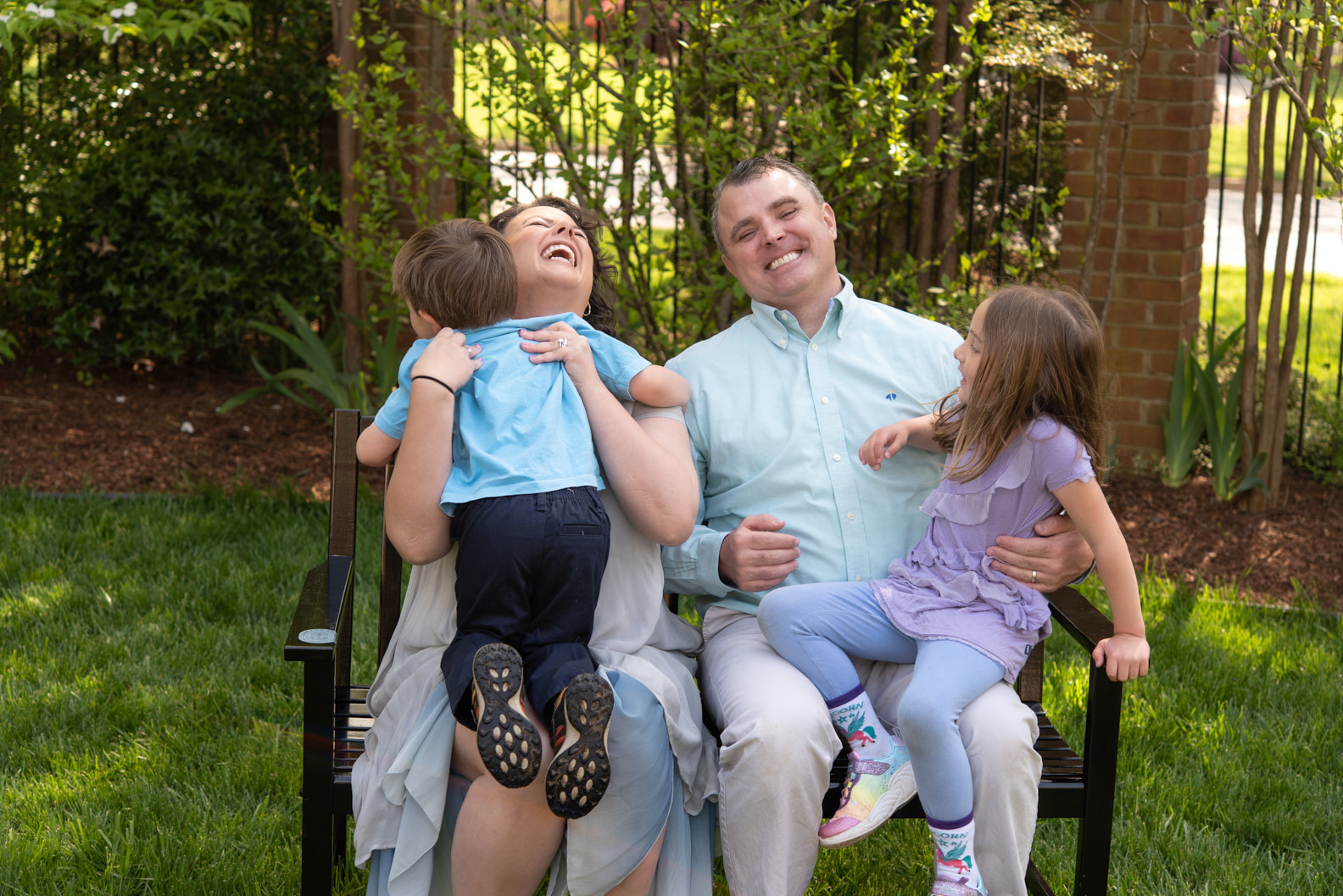 A family of four on a garden bench, laughing.