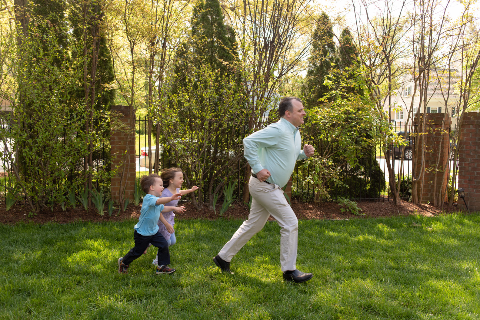 A father and his children running across the lawn.